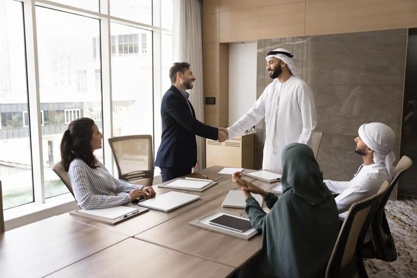 Empresários árabes e europeus apertam as mãos em uma reunião de equipe, discussão corporativa.