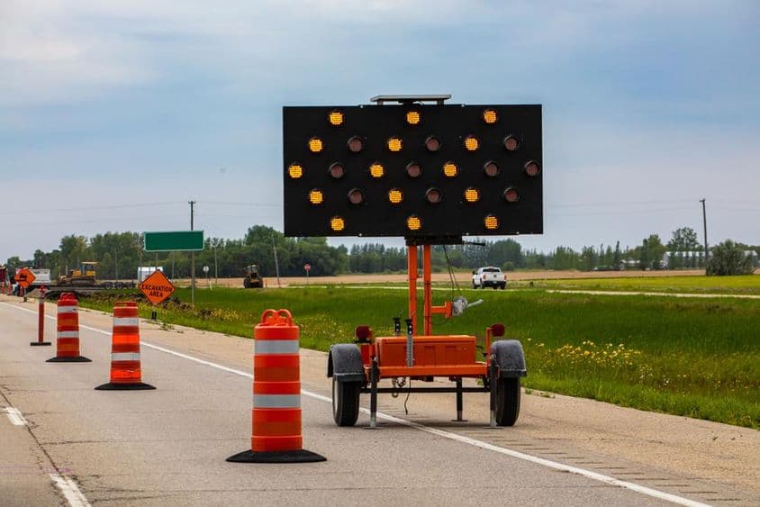Luzes laranjas piscando com setas e cones de estrada guiando os motoristas durante o fechamento de pistas.