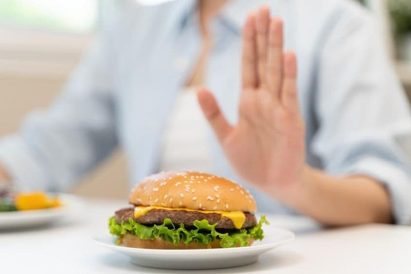 Uma mulher recusa um hambúrguer fast-food rico em gordura.