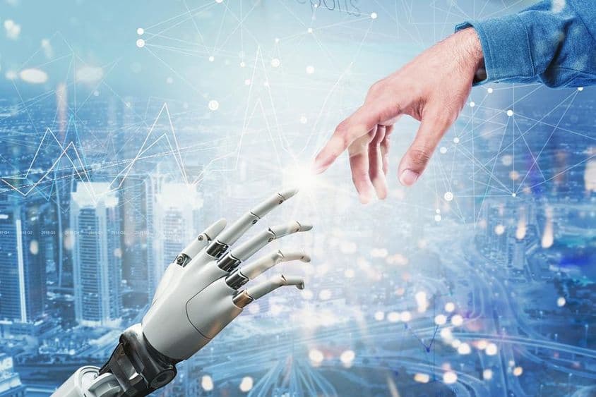 Mão robótica 3D encontrando mão humana sobre um cenário urbano futurista.