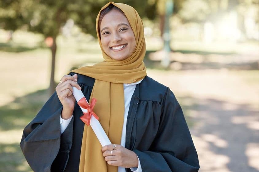 Estudante islâmico com um diploma em uma universidade ao ar livre.
