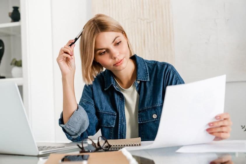 Freelancer refletindo enquanto prepara impostos em um laptop.
