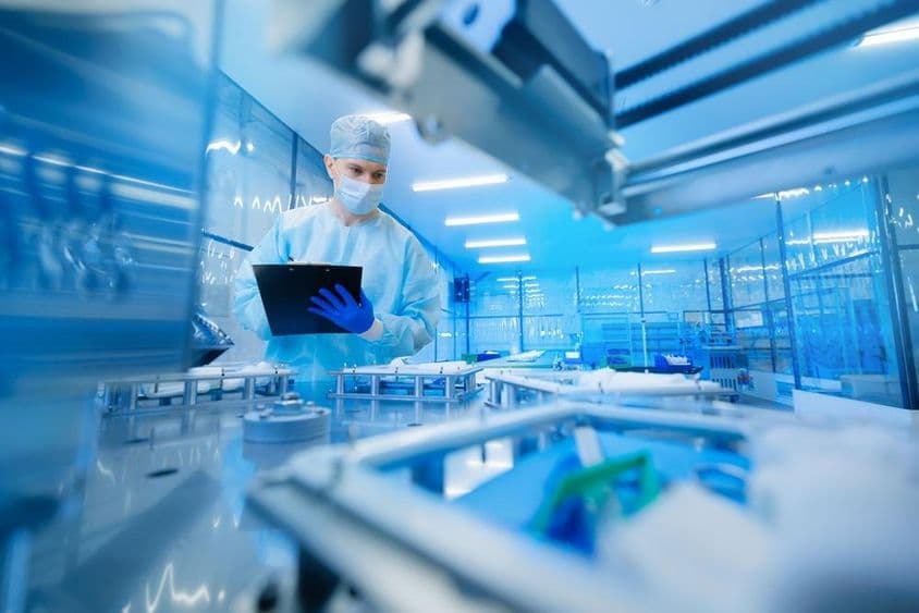 Trabalhador farmacêutico operando uma linha de produção na indústria farmacêutica.