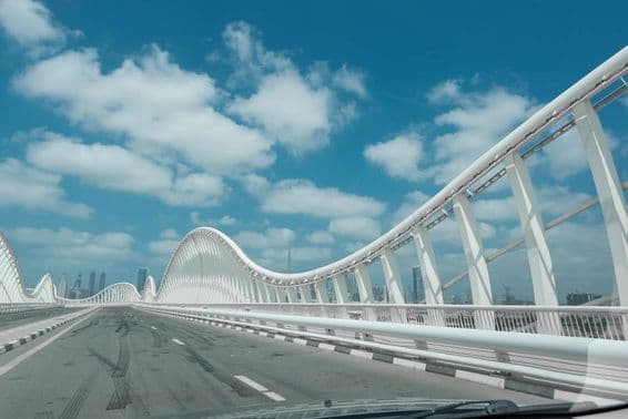 Ponte abstrata moderna com céu azul e nuvens ao fundo.
