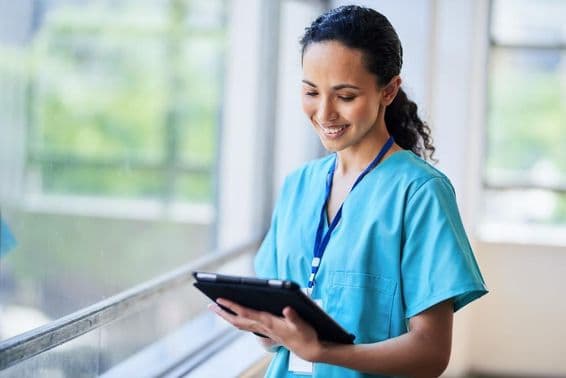 Enfermeira sorridente com tablet digital em uma moderna instalação médica.