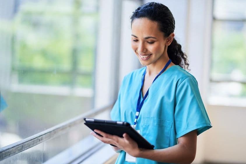 Enfermeira sorridente com tablet digital em uma moderna instalação médica.
