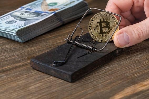 Moedas de criptomoeda Bitcoin na armadilha, presas com notas de 100 dólares americanos.