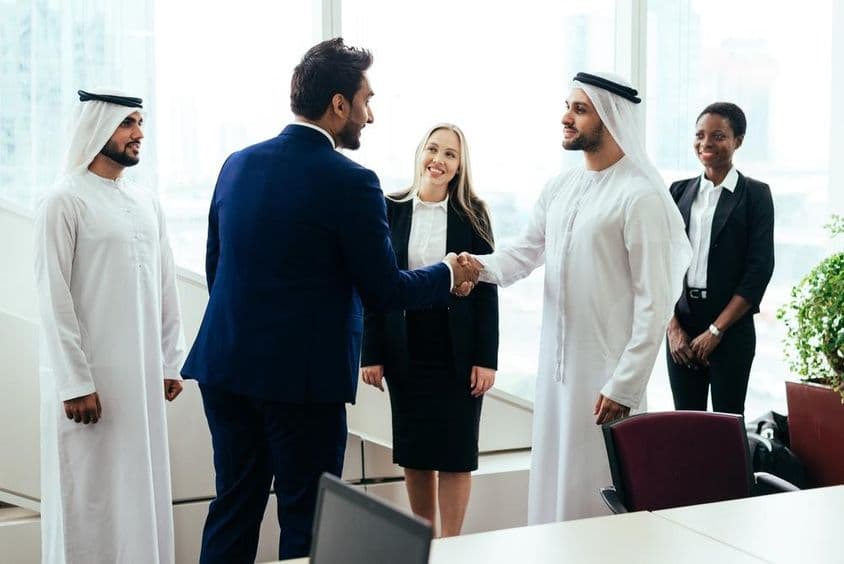 Uma equipe de negócios multinacional ocidental e do Oriente Médio trabalhando junta em um escritório em Dubai.