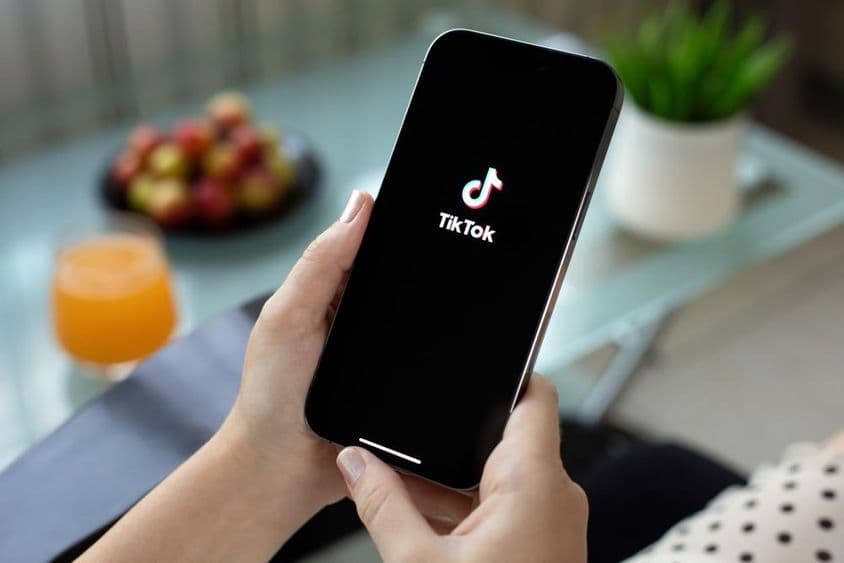 Apple iPhone 15 Pro Max na mão de uma mulher, vídeo do TikTok na tela.