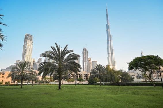 Dubai, Emirados Árabes Unidos, parque verde em área residencial com Burj Khalifa ao fundo.