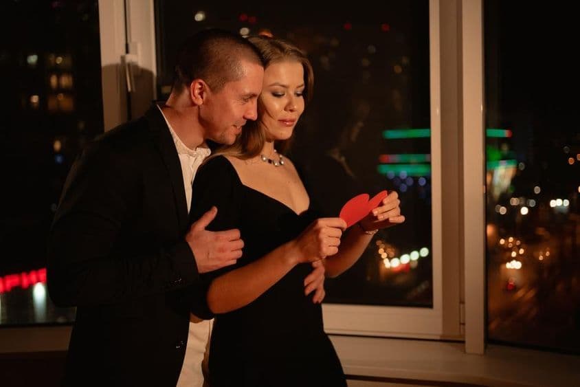 Casal apaixonado em um encontro de Dia dos Namorados, de pé junto à janela.