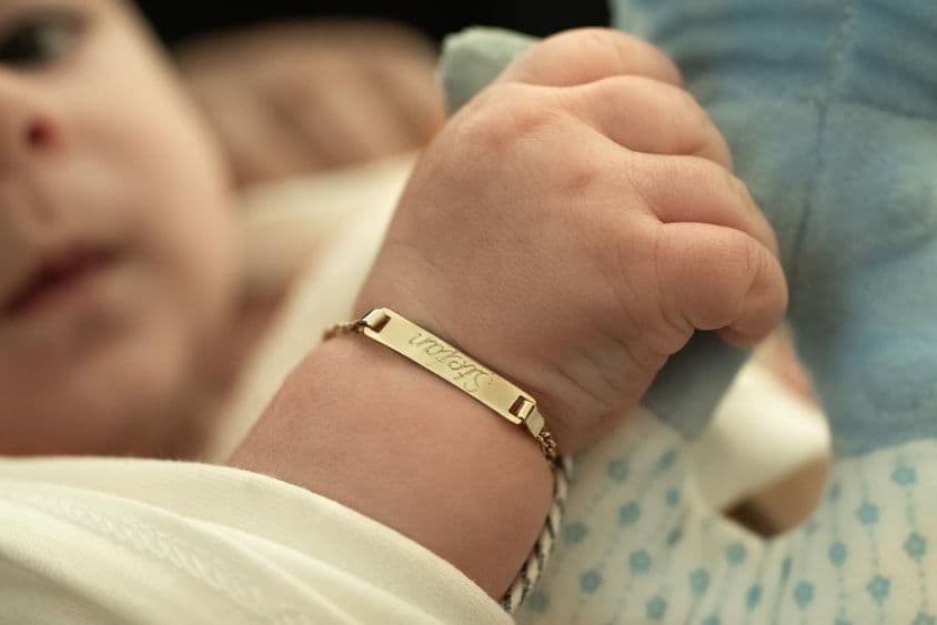 Um bebê com uma pulseira de ouro.