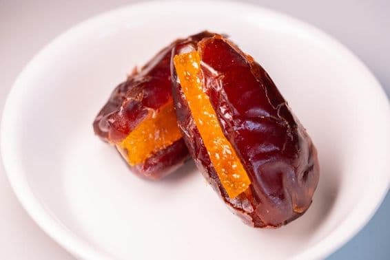Duas tâmaras enormes e frescas de Dubai com pedaços de laranja açucarados.