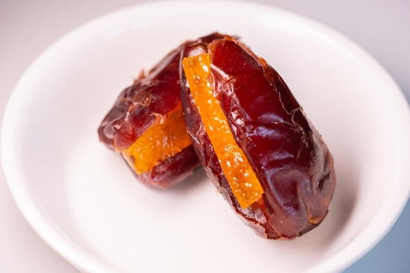 Duas tâmaras enormes e frescas de Dubai com pedaços de laranja açucarados.