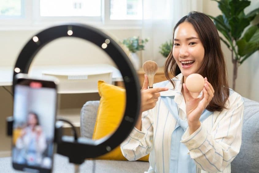 Jovem influenciadora mulher blogueira usando smartphone falando em um podcast de transmissão de vídeo.