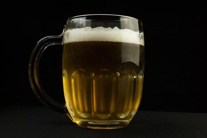 Caneca de cerveja com espuma no topo.