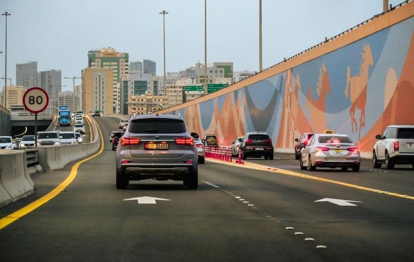 Tráfego de carros em uma rodovia com arranha-céus ao fundo em Dubai, Emirados Árabes Unidos.