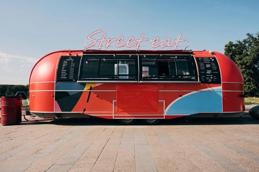 Caminhão de comida vermelho, venda de fast food no meio da rua ou praça.