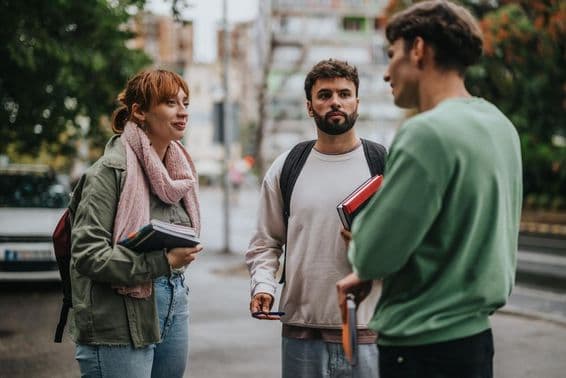 Grupo de estudantes discutindo ao ar livre com livros nas mãos.
