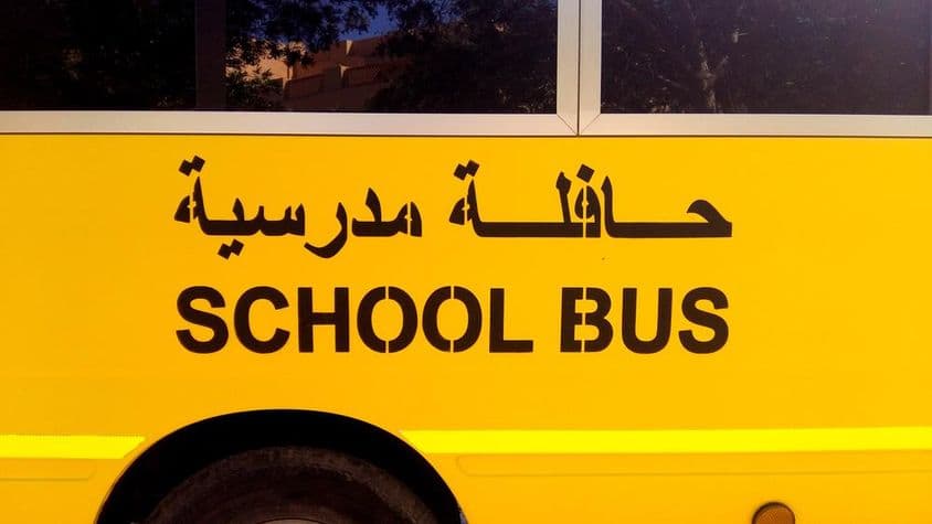 Ônibus escolar em Dubai com texto em árabe.
