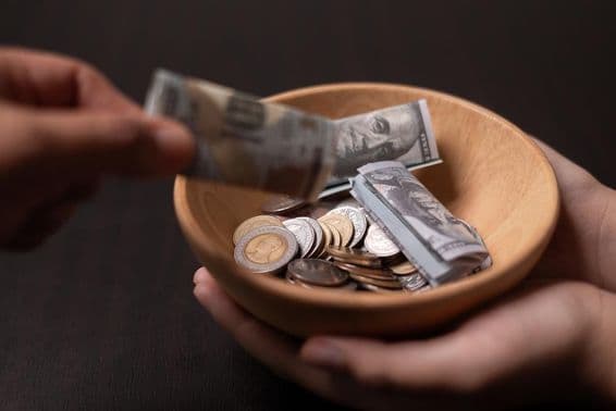 Doação sendo coletada em um vaso de madeira.