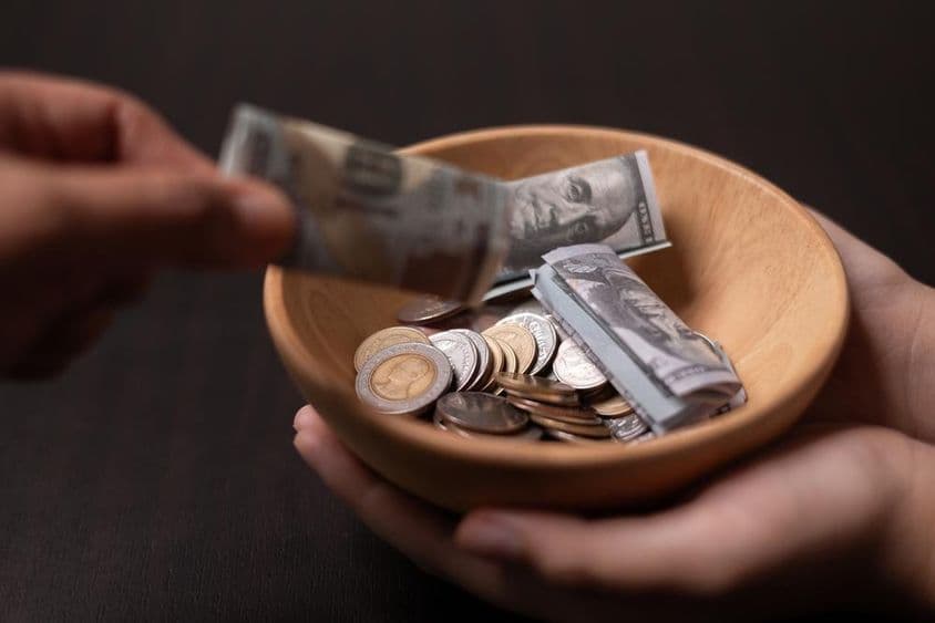 Doação sendo coletada em um vaso de madeira.