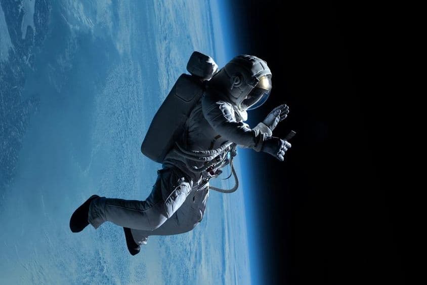 Astronauta mulher fazendo uma chamada de vídeo em seu telefone durante uma caminhada espacial no espaço profundo.