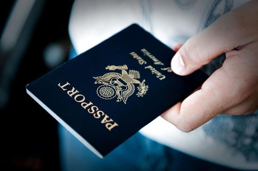 Homem segurando um passaporte azul.