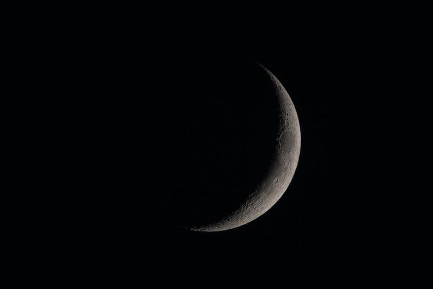 Lua nova detalhada no céu escuro.