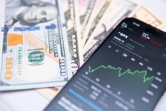 O índice SP500 na tela de um smartphone, com fundo de dólar americano.