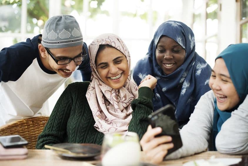 Grupo de estudantes olhando uma lição em um celular.