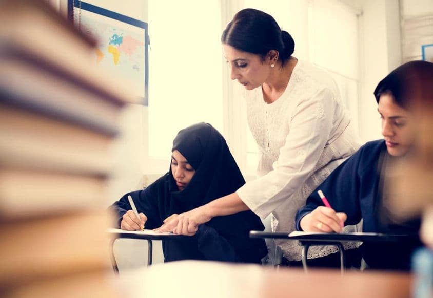 Meninas muçulmanas estudando em uma sala de aula.