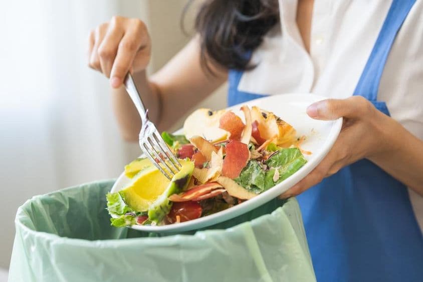 Composto de desperdício de alimentos, jovem dona de casa raspando resíduos com um garfo.