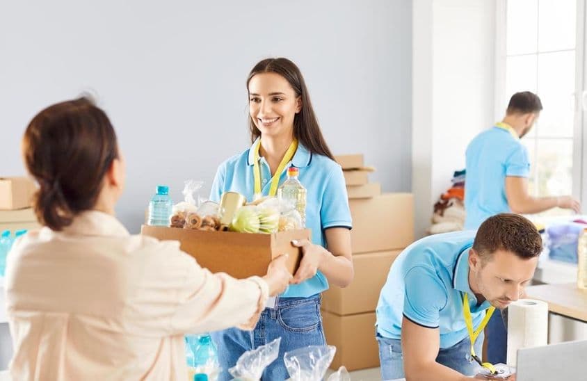 Jovem voluntário distribuindo caixa de doação de alimentos para necessitados em uma fundação de caridade.