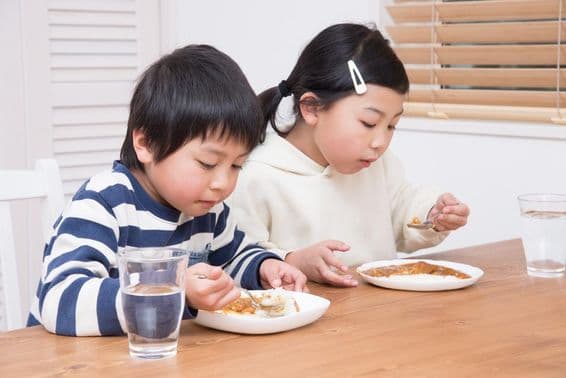 Criança come arroz com curry em casa.
