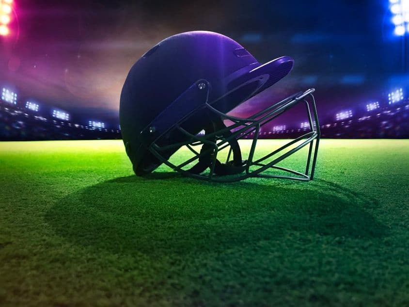 Capacete de críquete visto de baixo sobre grama verde.