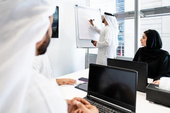 Um grupo de homens de negócios em trajes tradicionais emiradenses em uma reunião em um escritório em Dubai.