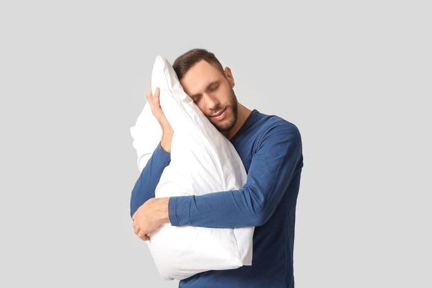 Jovem de pijama com travesseiro macio.