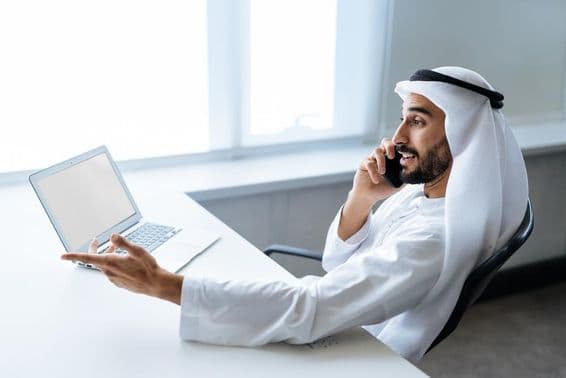 Um empresário bem-sucedido com traje tradicional Emirati branco trabalhando em Dubai.