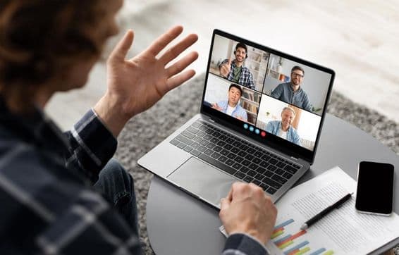 Um homem sentado à mesa, participando de uma videoconferência em seu laptop.