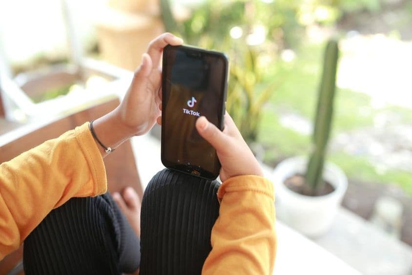 Uma criança assistindo conteúdo de mídia do TikTok em um celular.