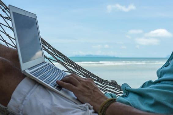 Um homem trabalhando em um computador em uma rede com um laptop na praia de Dubai.