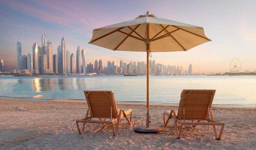 Praia linda em Dubai com 2 espreguiçadeiras e um guarda-sol.
