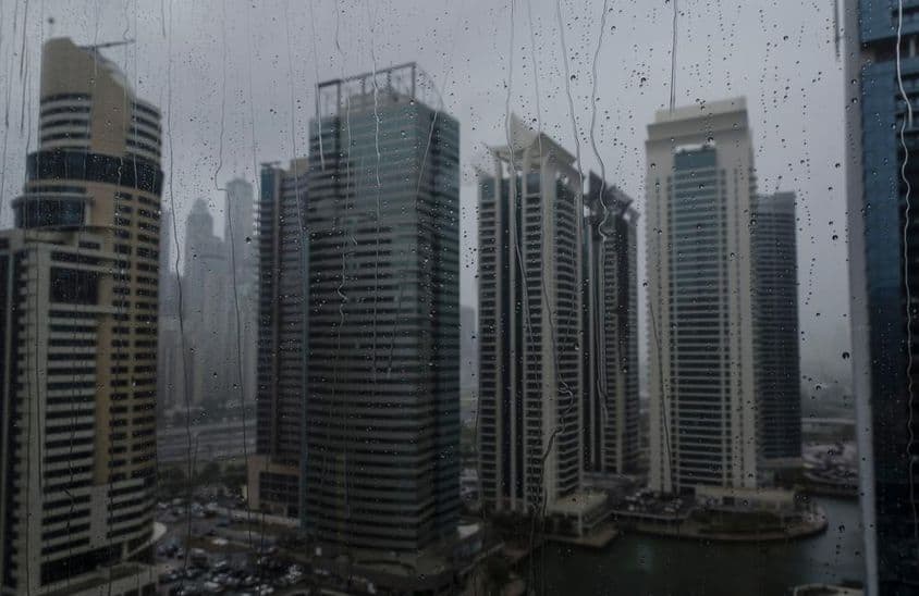 Janela molhada mostrando o moderno horizonte comercial de Dubai.