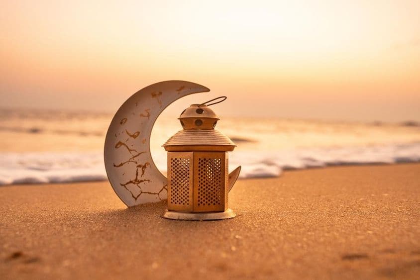 Lua crescente tradicional iluminada por velas na praia.
