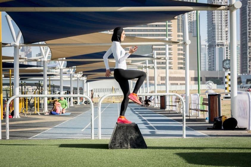 Mulher árabe exercitando-se, usando hijab.