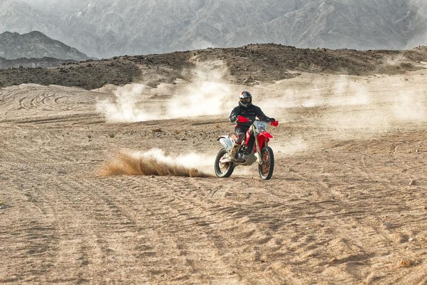 Motociclista usando capacete andando no deserto