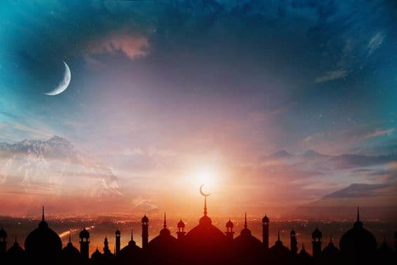 Domos de mesquita contra um céu azul crepuscular com uma lua crescente ao fundo.