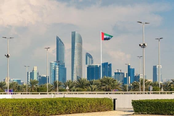 Skyline icônico de Abu Dhabi com um arranha-céu moderno e bandeira nacional visível.