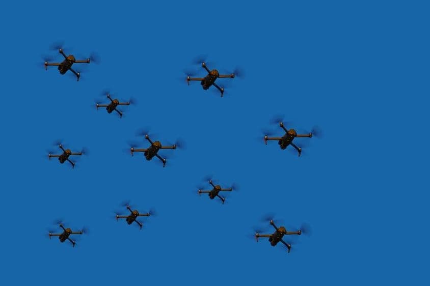 Drones voando em formação contra um céu azul.